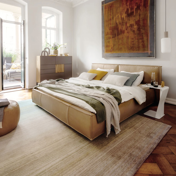 Hellbraunes Bett mit Lederbezug mit Nachttisch und Kommode in stylischem Schlafzimmer